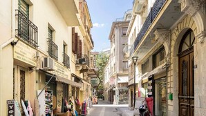 A narrow street lined with buildings, some with balconies and shops on the ground floor. - Athens' Best Location! ~Stunning & Spacious Studio (Athens)