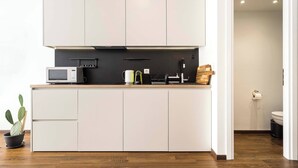 A modern kitchen with white cabinets, a microwave, a kettle, and a sink. - Athens' Best Location! ~Stunning & Spacious Studio (Athens)