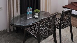 Une petite pièce privée, avec une table ronde en verre, deux chaises, un lit et un rideau.