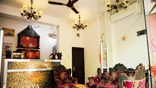 Un espace d’accueil avec une enseigne « SURYA », un comptoir d’accueil et des meubles traditionnels aux motifs rouges.
