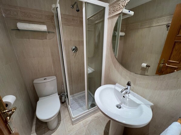 A bathroom with a toilet, a glass-enclosed shower, and a sink.