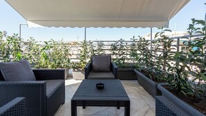 A rooftop patio with wicker furniture, potted plants, and a canopy. - Prime 3BR Exarcheia Penthouse | Huge Terrace (Athens)