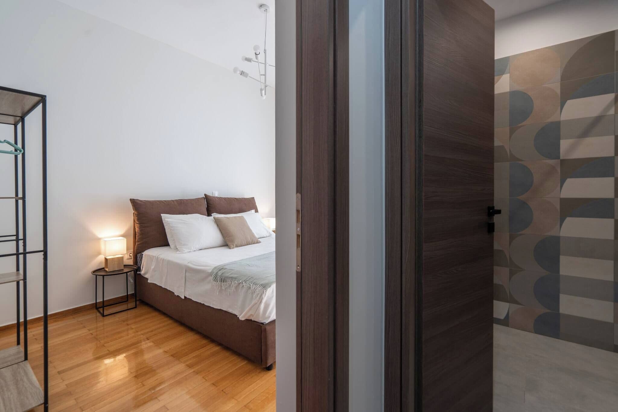 A bedroom with a bed, bedside table, and a wall-mounted light fixture.