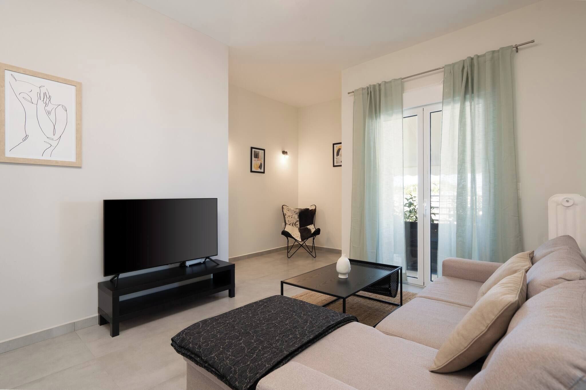 A modern living room with a flat-screen TV, a sofa, a coffee table, and a chair.