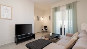 A modern living room with a flat-screen TV, a sofa, a coffee table, and a chair. - Prime 3BR Exarcheia Penthouse | Huge Terrace (Athens)