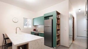 A modern kitchen with a marble island, green cabinets, and a stainless steel refrigerator. - Prime 3BR Exarcheia Penthouse | Huge Terrace (Athens)