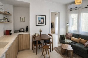 Un espacio habitable compacto con kitchenette, comedor y zona de estar.