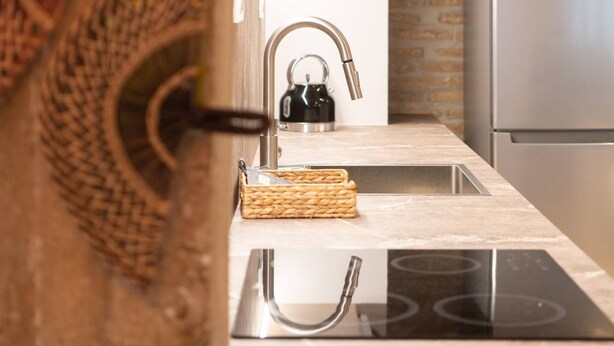 Una cocina moderna con estufa integrada, pileta de acero inoxidable y refrigerador.