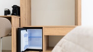 A compact, modern room with a built-in refrigerator, a small coffee maker, and a chair. - Olivia's Home By DomusExtra (Naples)