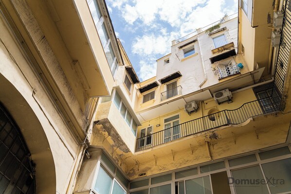 A multi-story building with balconies, air conditioning units, and a clear sky. - Olivia's Home By DomusExtra (Naples)