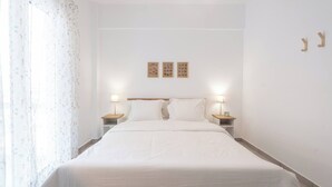 A neatly made bed with white linens, two bedside lamps, and three framed pictures on the wall. - Bright 2BR Apartment By Metro Near Acropolis (Athens)