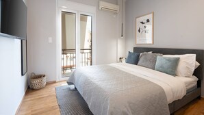 Een slaapkamer met een bed, een wandairconditioner, een lijst met een afbeelding en een balkondeur.