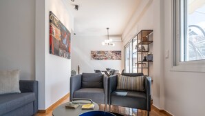 Een moderne woonkamer met een bank, fauteuil, salontafel en een boekenkast.