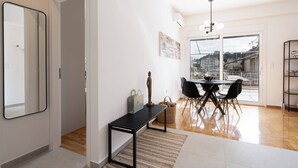 Een moderne woonkamer met een eethoek, grote ramen en uitzicht op de stad.