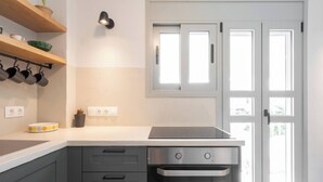 Une cuisine moderne dotée d’un four encastré, d’un plan de travail avec une bouilloire et d’une fenêtre offrant une vue agréable.