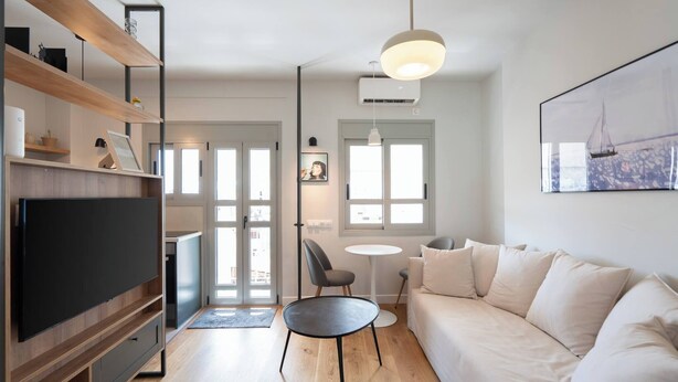 Un salon moderne doté d’un téléviseur à écran plat, d’étagères en bois, d’un canapé, d’une table basse ronde et d’un luminaire suspendu.