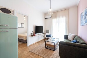 A modern living room with a television, sofa, coffee table, and a light blue refrigerator.