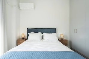 A neatly made bed with a blue quilt, white pillows, and two bedside lamps.