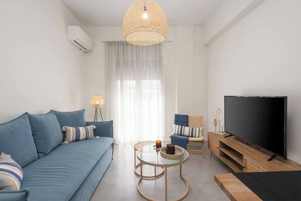 A modern living room with a sofa, TV, and a glass coffee table.