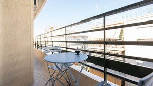 A balcony with a round table and chairs, a small bowl, and a view of buildings.