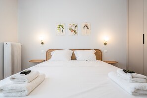 Habitación de hotel con cama, dos mesitas de noche, un radiador y tres lámparas fijadas a la pared.