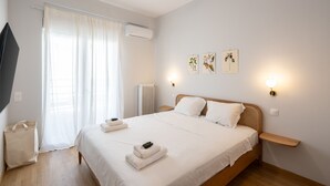 A bedroom with a bed, a ceiling fan, a window with curtains, wall-mounted lights, and a radiator.