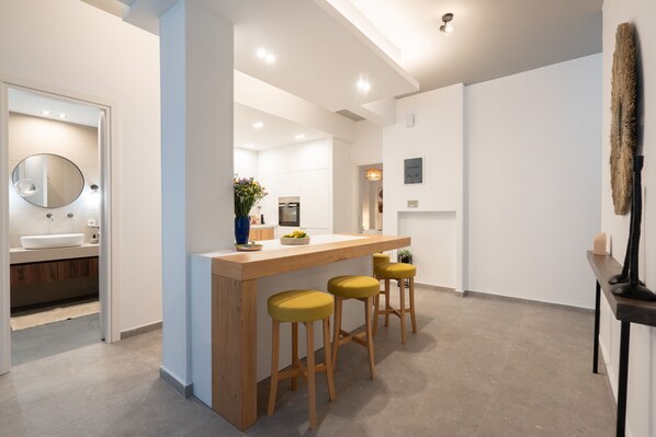 A modern kitchen with a wooden island, bar stools, and a large mirror. - My Happy Greek Home (Athens)