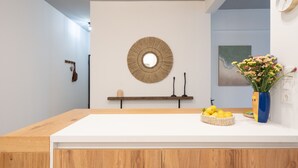 Una cocina moderna con encimera de madera, un espejo redondo, una repisa con velas y un florero con flores.