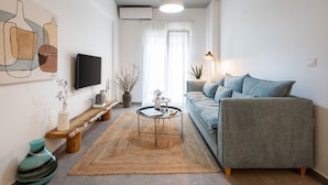 Una sala de estar moderna con un sofá, una mesa de centro, un televisor y un cuadro en la pared.