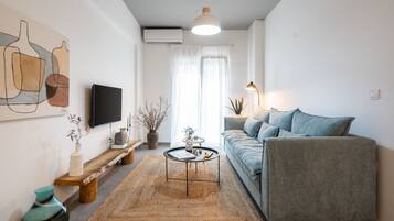 A modern living room with a sofa, a coffee table, a TV, and a painting on the wall.