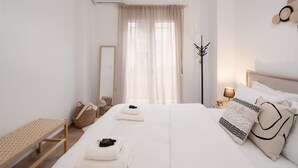 Una habitación de hotel con cama, mesita de noche, lámpara y perchero.