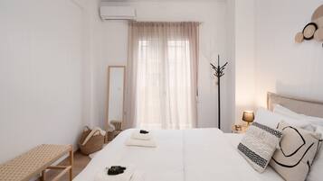 A hotel room with a bed, bedside table, lamp, and a coat rack.