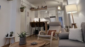 Un salon moderne comprenant un coin repas, un canapé gris, une table basse en bois et un luminaire suspendu au design géométrique original.