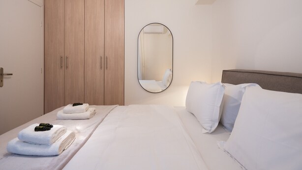 A hotel room with a bed, a wooden wardrobe, and a mirror.