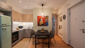 A modern kitchen with a dining table, chairs, and a painting on the wall.