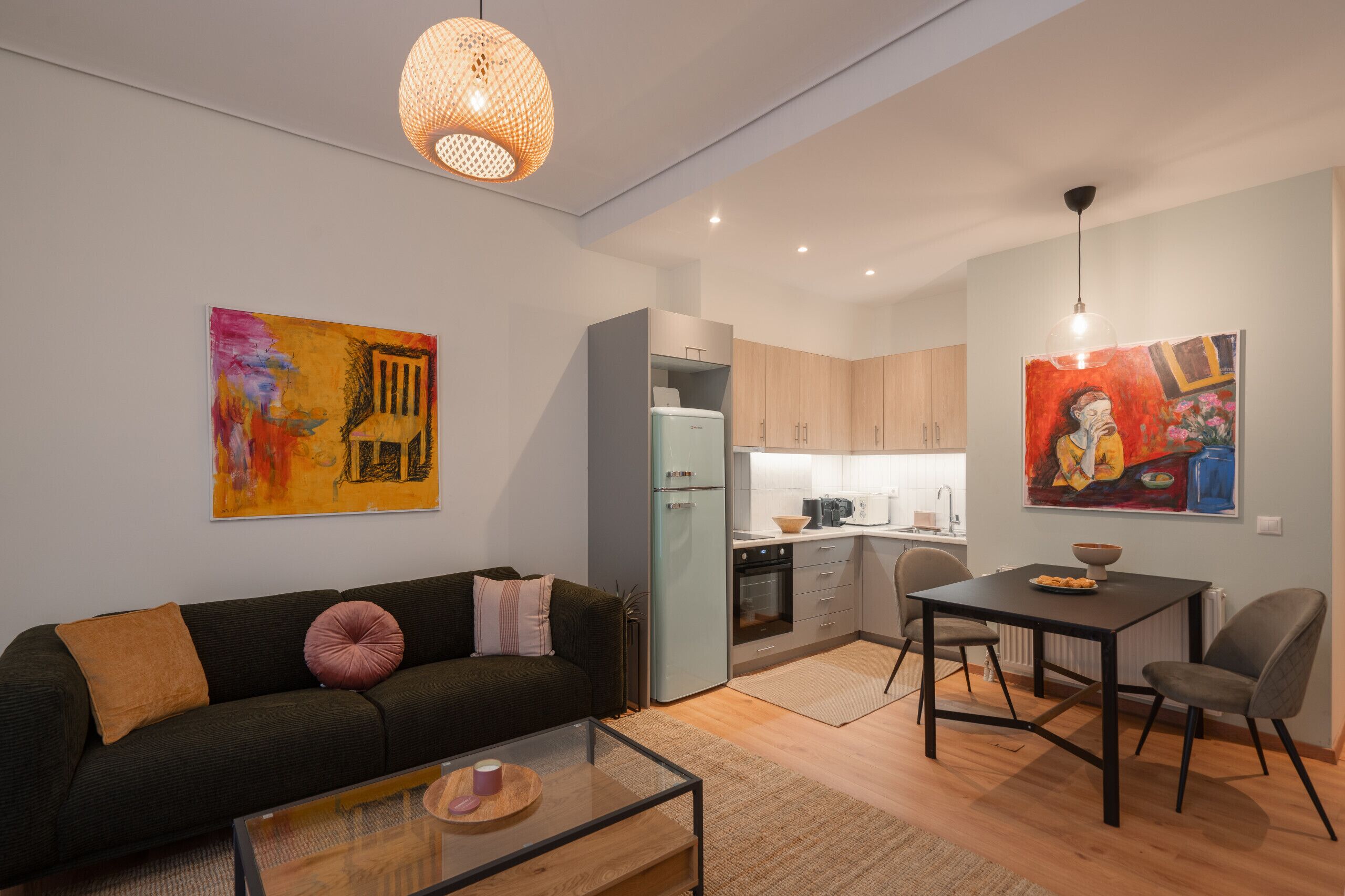 Un apartamento moderno con sala de estar, kitchenette, comedor y una mesa de centro de vidrio.
