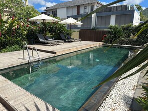 A clear swimming pool with a wooden deck, lounge chairs, and umbrellas. - 🌊Brand-New Beachfront 3BR | Terrace & Ocean Access / Ocean Legend in Tamarin🏝️ (Tamarin)