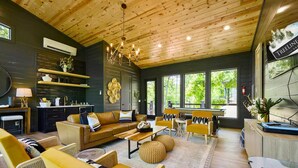 Ein modernes Wohnzimmer mit Holzboden, Kamin und großen Fenstern mit Blick ins Freie.