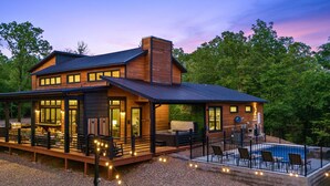 Ein modernes Haus mit einer großen Terrasse, einem Pool und einem überdachten Außenbereich.