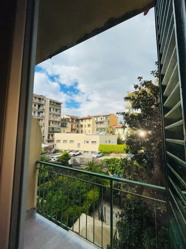 Un balcone con vista su una zona residenziale, con edifici a più piani e auto parcheggiate.