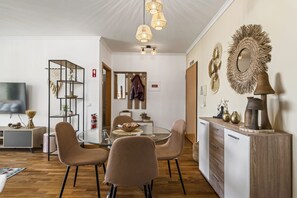 Enjoy meals around the central dining table with four chairs, surrounded by a television and a bookshelf with decorative items.