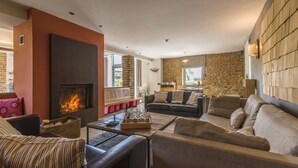 A cozy living room with a fireplace, comfortable seating, and a stone accent wall.