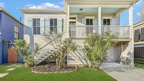 A two-story house with a front porch, a staircase leading to the second floor, and a garage. - The Happy Hut - walk to the beach (Galveston)