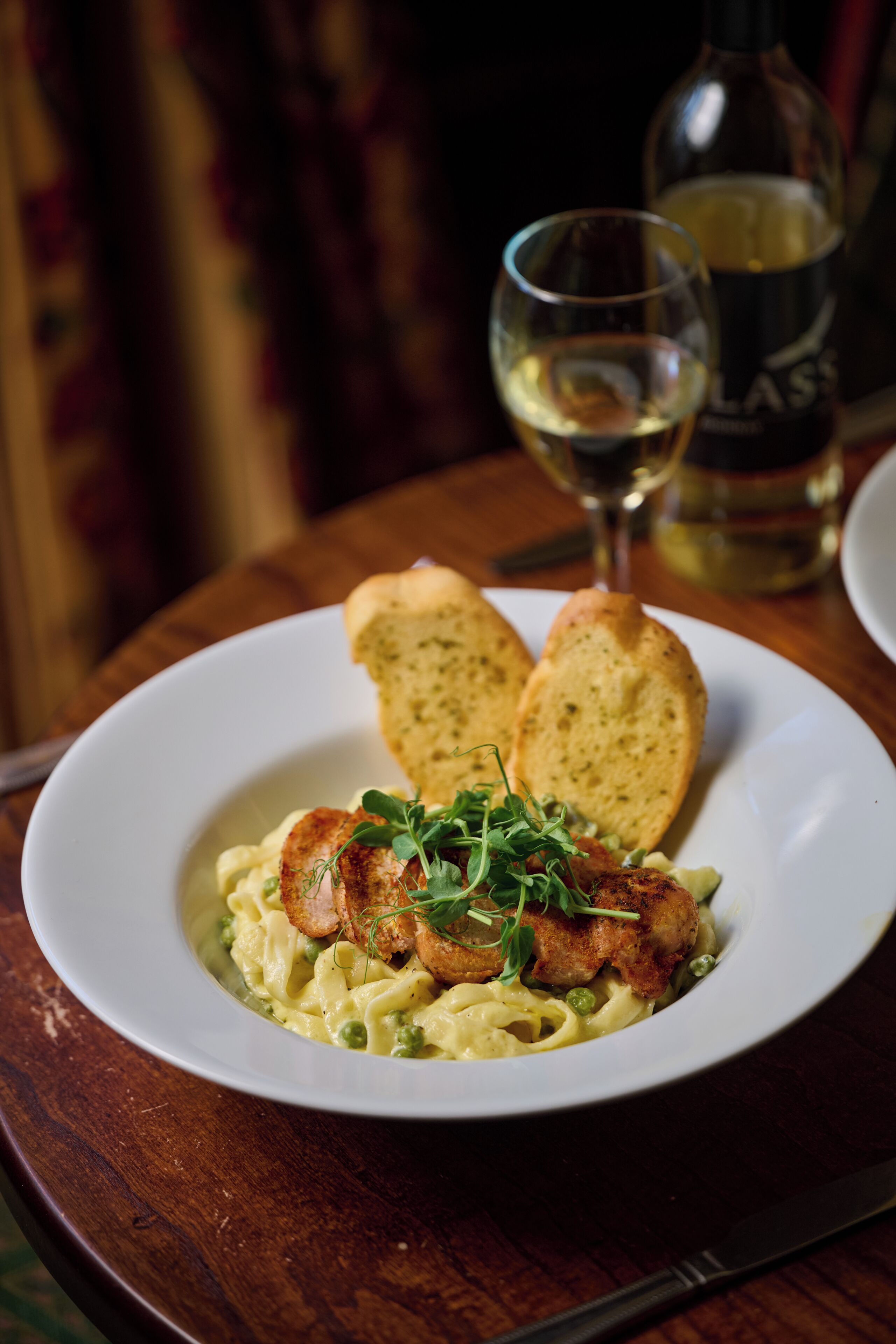A plate of food with bread and a bottle of wine on a table.