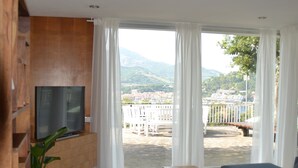 Una sala de estar con televisor, sofá y vista a un balcón con barandilla.