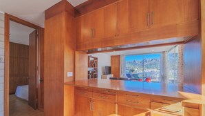 Una cocina moderna con armarios de madera y un amplio ventanal con vistas a una montaña panorámica.