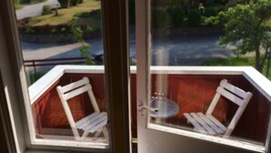 A balcony with a white chair and a small table.