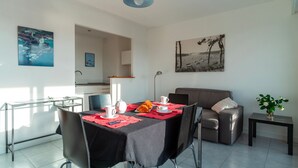 Ein Essbereich mit einem für zwei Personen gedecktem Tisch, einer Couch und Kunstwerken an den Wänden.