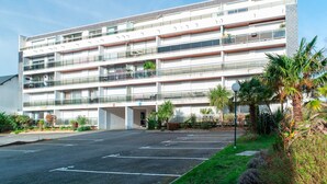 Ein mehrgeschossiges Gebäude mit Parkplatz davor.