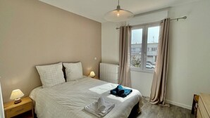 Une chambre à coucher avec un lit, des lampes de chevet, une fenêtre avec des rideaux et un radiateur.